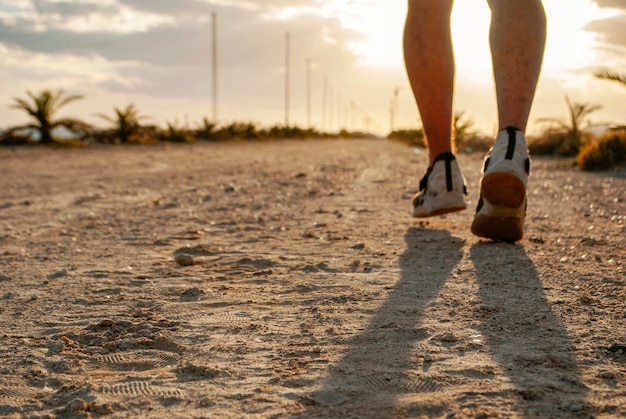 Un homme court le long de la route sur la plage au coucher du soleil.