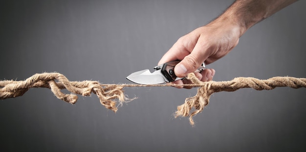 Homme avec un couteau coupant la corde effilochée Risque