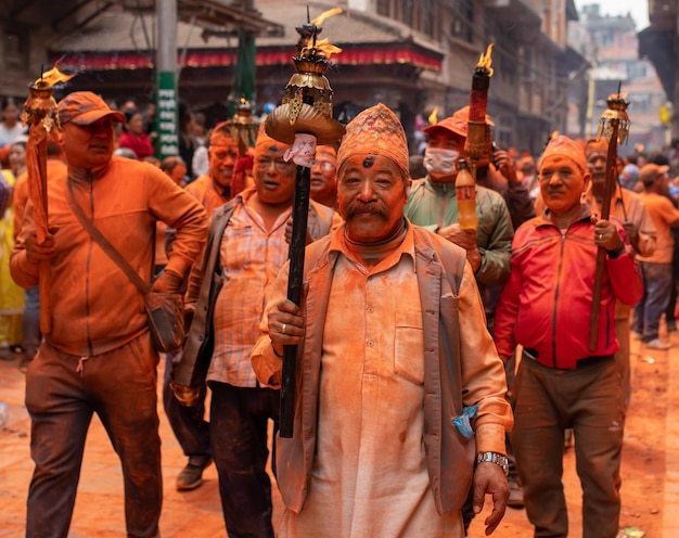 Un homme couvert de peinture orange marche avec une torche à la main.