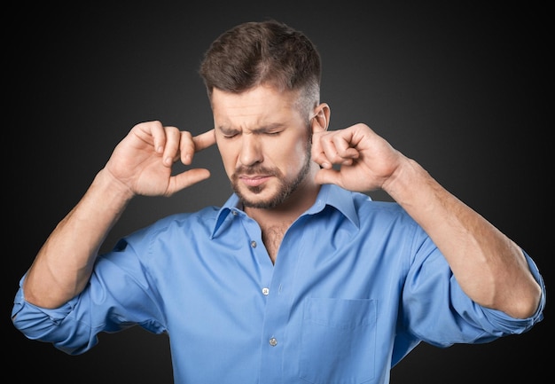 L'homme couvre ses oreilles avec ses mains sur le fond