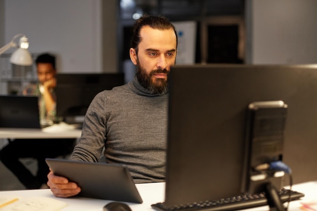 Un homme créatif avec un ordinateur qui travaille tard au bureau.