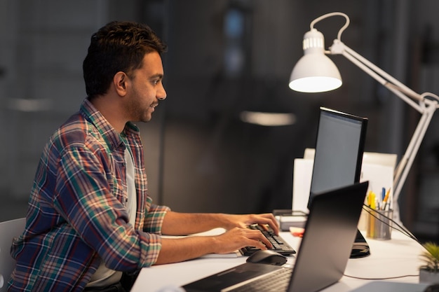 homme créatif avec ordinateur travaillant au bureau de nuit