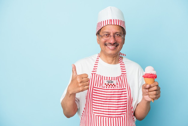 Homme de crème glacée américain senior tenant une glace isolée sur fond bleu souriant et levant le pouce vers le haut