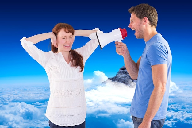 Homme criant à travers un mégaphone contre le sommet de la montagne à travers les nuages