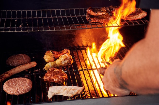 Un homme cuisinant des barbecues grillés sur le feu à l'extérieur