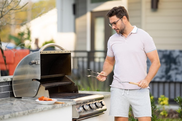 Homme cuisinant de la viande sur un barbecue dans l'arrière-cour de la maison bel homme préparant un barbecue barbecue c