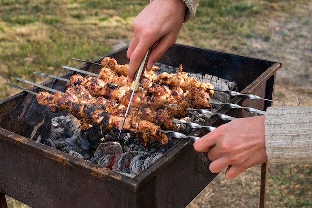 L'homme cuisine, seulement les mains, il coupe de la viande ou du steak pour un plat. Délicieuse viande grillée sur le gril. Week-end barbecue. Mise au point sélective.