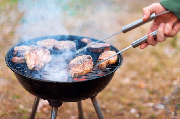 L'homme cuisine, seulement les mains, il fait griller de la viande ou du steak pour un plat. Délicieuse viande grillée sur le gril. Week-end barbecue. Mise au point sélective.
