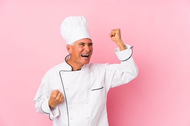 Homme cuisinier d'âge moyen isolé levant le poing après une victoire, concept gagnant.