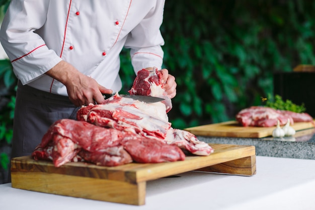 Un homme cuisinier coupe la viande avec un couteau dans un restaurant.