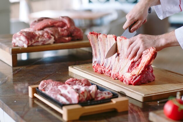 Un homme cuisinier coupe la viande avec un couteau dans un restaurant.