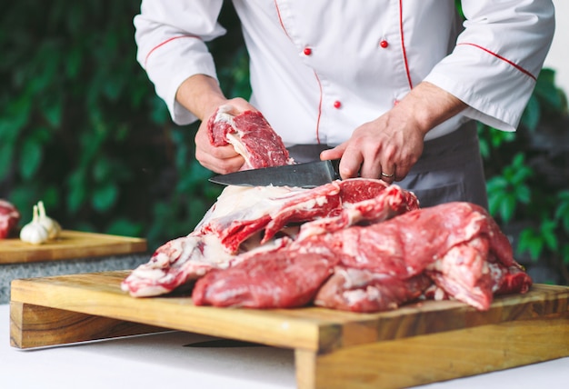 Un homme cuisinier coupe la viande avec un couteau dans un restaurant.