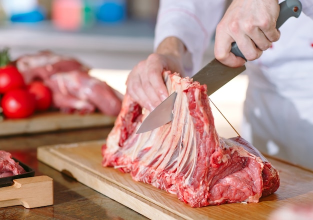 Un homme cuisinier coupe la viande avec un couteau dans un restaurant.