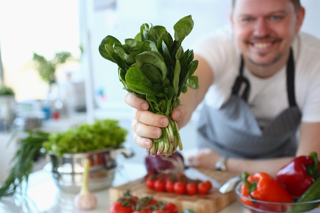 L'homme cuisinier tient une salade d'oseille verte fraîche dans la cuisine avec des légumes