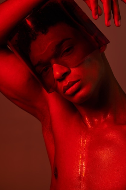 Homme cyberpunk et studio de lumière au néon rouge pour l'esthétique de la mode des lunettes futuristes Lunettes de vaporwave de conception d'art créatif et visage de modèle sur fond rouge graphique pour le futur portrait de beauté du métaverse