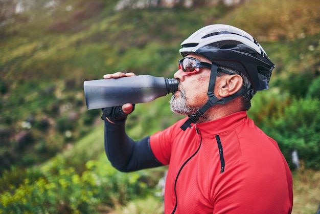 Homme cycliste et eau potable en montagne dans un régime de remise en forme ou une alimentation naturelle au repos ou en pause après un exercice de cyclisme Homme assoiffé avec une boisson minérale pour la durabilité dans l'entraînement cardio