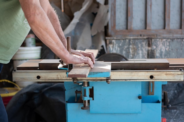 Un homme dans un atelier coupe une planche de bois à l'aide d'une scie circulaire