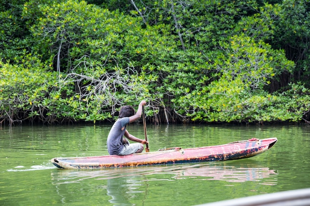 Homme dans le bateau flottant sur la rivière dans la jungle tropicale, Ceylan. Paysage du Sri Lanka