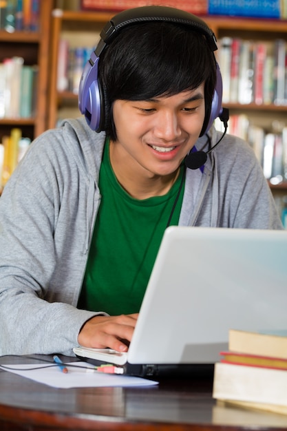 Homme dans la bibliothèque avec un ordinateur portable et des écouteurs