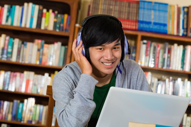 Homme dans la bibliothèque avec un ordinateur portable et des écouteurs