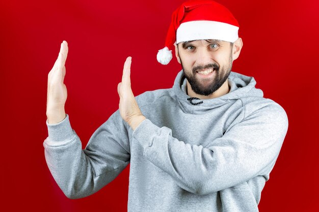 Un homme dans un bonnet de Noël de Noël tient des jouets de Noël, des balles et des cris dans sa main.