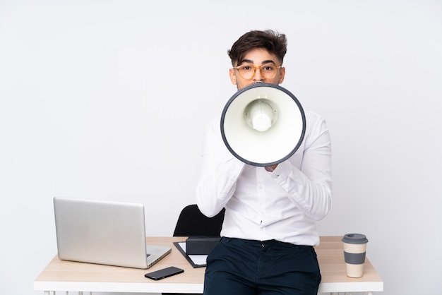 Homme dans un bureau isolé sur un mur blanc criant à travers un mégaphone