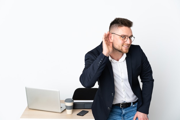 Homme dans un bureau isolé sur mur blanc à l'écoute de quelque chose en mettant la main sur l'oreille