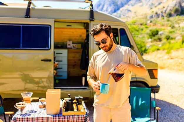 Photo un homme dans une charmante roulotte fait du café à l'extérieur dans les montagnes en journée ensoleillée d'été