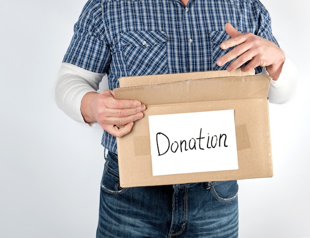 Homme dans une chemise à carreaux bleu et un jean est titulaire d&#39;une grande boîte en papier brun avec le don d&#39;inscription