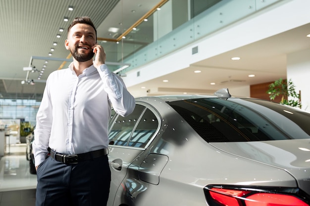 Un homme dans un concessionnaire automobile parle bien au téléphone