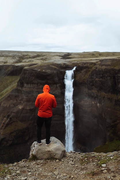 L'homme dans un coupe-vent rouge à la cascade de Haifoss, Islande