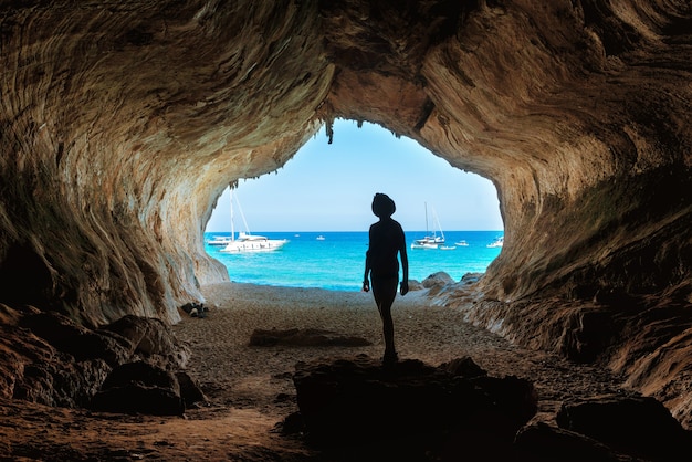 Un homme dans la grande grotte, vue de l'intérieur. Côte méditerranéenne, Sardaigne, Italie.