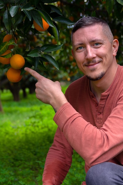 Un homme dans le jardin d'orangers et des oranges mûres sur les branches des arbres