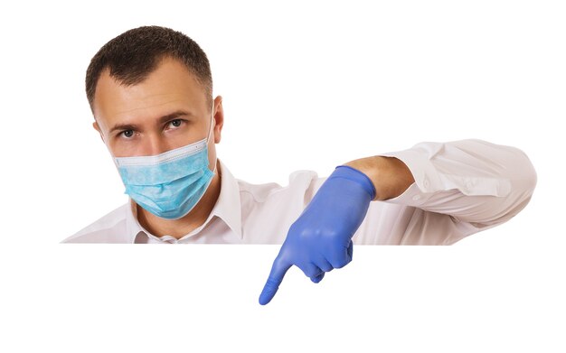 Un homme dans un masque médical et des gants montre son index vers le bas isolé sur un modèle médical blanc