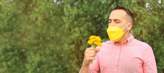 Un homme dans un masque médical sur son visage avec un bouquet de fleurs dans sa bannière à la main avec place pour le texte