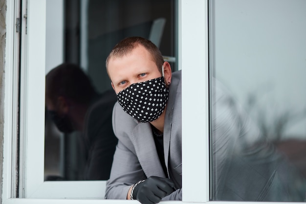 Homme, dans, masque noir, et, gants médecine, regarder fenêtre, coronavirus, quarantaine