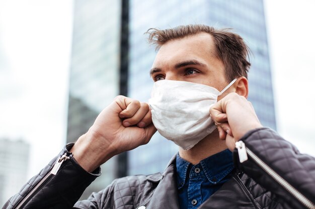 Homme dans un masque de protection debout sur une rue de la ville