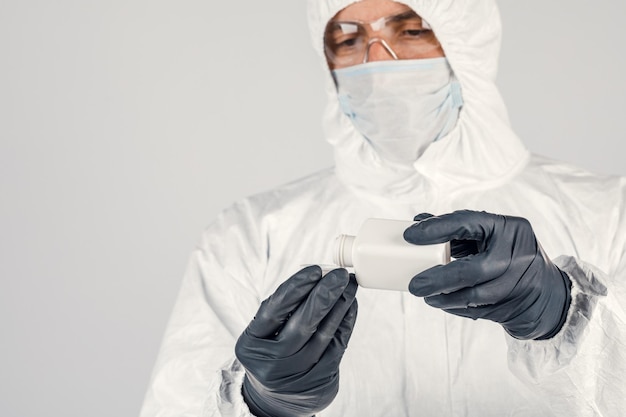 Un homme dans un masque de protection médicale tenant un désinfectant pour les mains