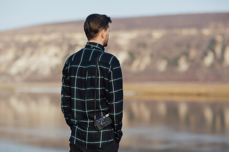 Photo homme dans la montagne près du lac tenant un vieil appareil photo