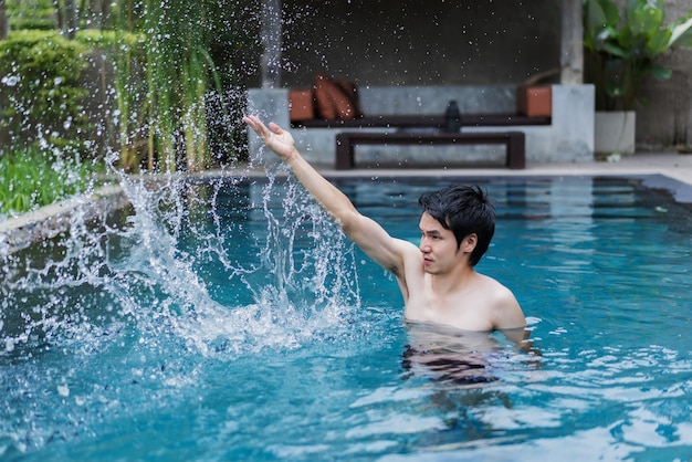 homme dans la piscine et jouant des éclaboussures d&#39;eau