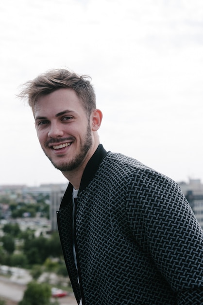 Un homme dans un pull gris avec une fermeture éclair posant.