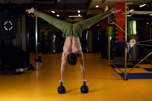 Photo un homme dans un rack sur ses mains reposant sur les poids. acrobaties