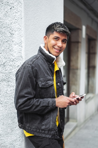 Homme dans la rue d'une ville avec un téléphone à la main en regardant la caméra