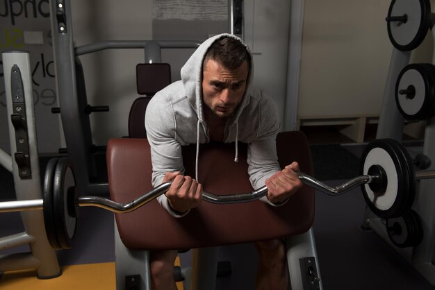 Homme dans la salle de gym exerçant des biceps avec des haltères