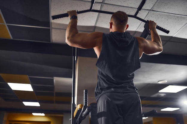 Homme dans la salle de gym faisant des exercices sur la barre transversale dans la salle de gym