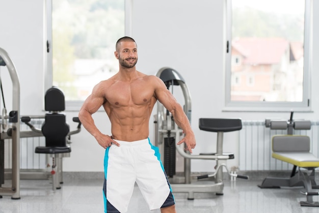 Homme dans la salle de gym montrant son corps bien formé