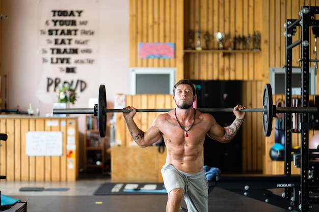 Homme dans une salle de sport faisant des fentes avec poids dans une salle de sport