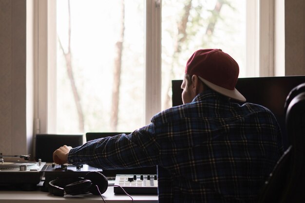 Un homme dans le studio de musique à domicile créant une nouvelle chanson avec un équipement vintage