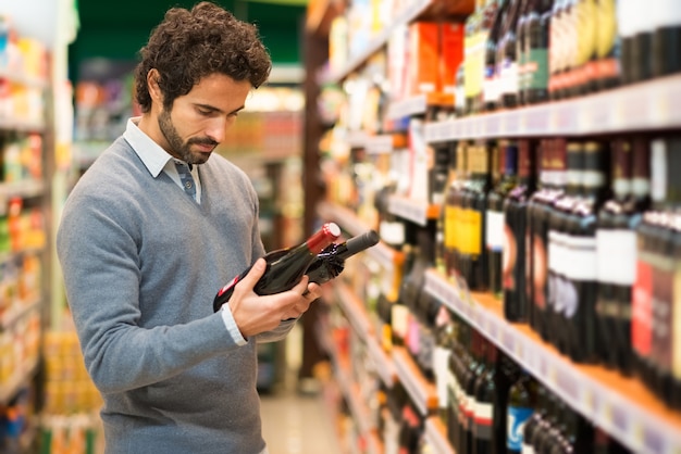 Homme dans un supermarché en choisissant un vin