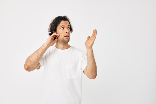 Homme dans un t-shirt blanc geste de la main fond clair